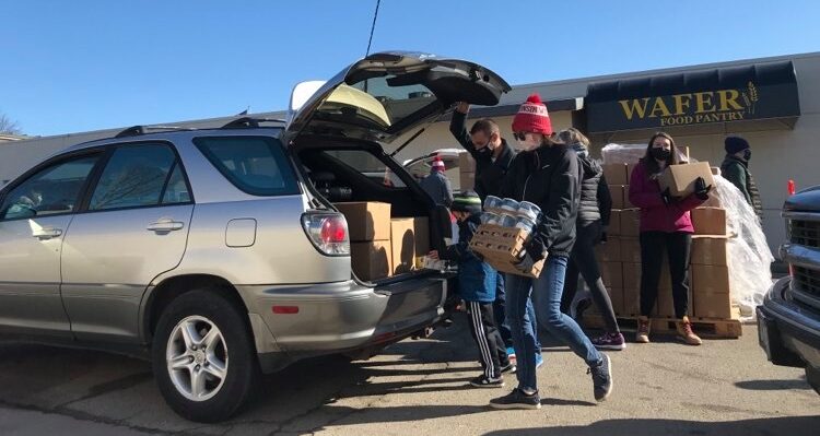 people loading food into back of SUV