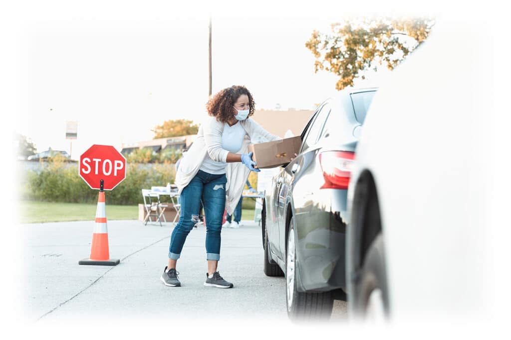 Woman handing food box to person in car